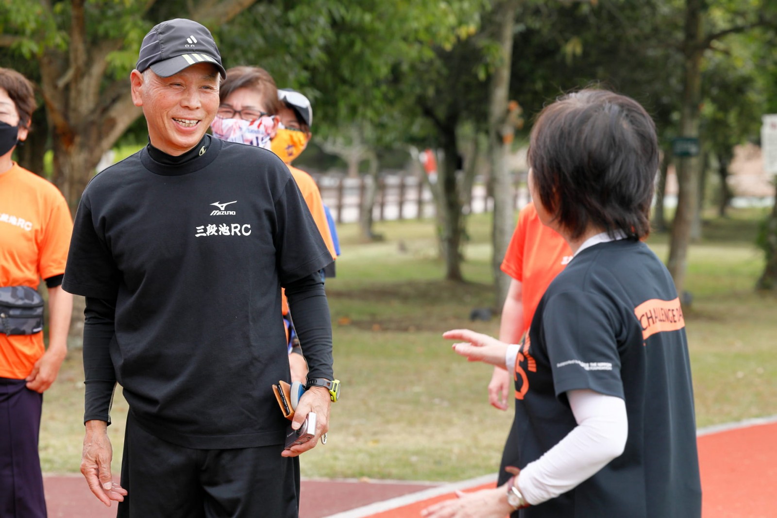 Omachi, shown here speaking with Masuda, is the leader of a local running club.