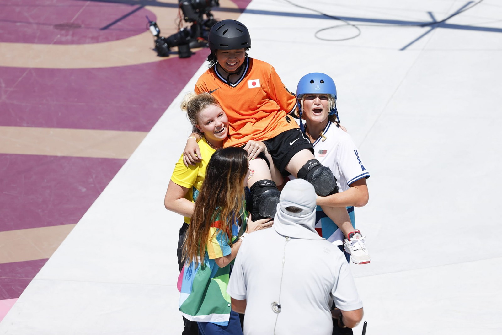 Athletes from other countries lift Misugu Okamoto on their shoulders after she fell attempting an indie flip during the Tokyo 2020 women’s skateboarding park finals. ©Photo Kishimoto