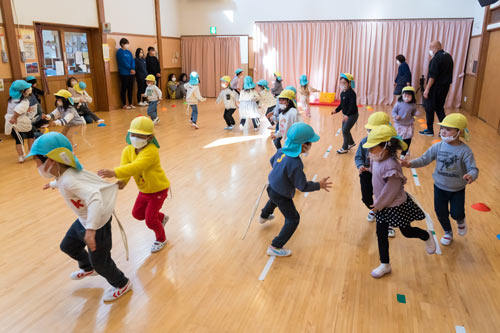 黄と青のチームに分かれてお尻につけたロープの尻尾を取り合う子どもたち