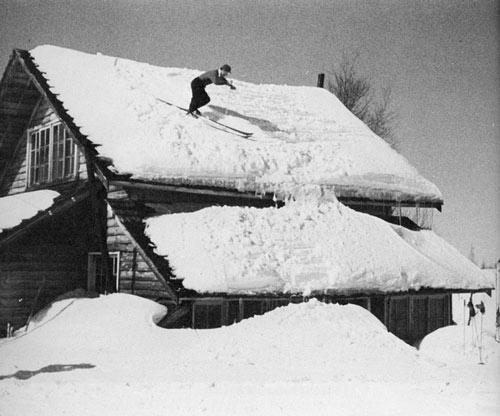 雪が積もった屋根をスキーで滑る猪谷千春