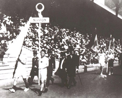 1912年ストックホルム大会の開会式で「NIPPON」のプラカードを持ち行進する金栗四三